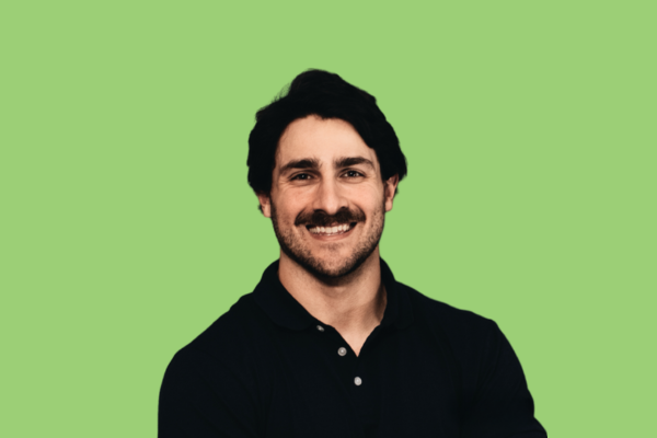 Black and white portrait of a dance instructor posing in front of a dark background.